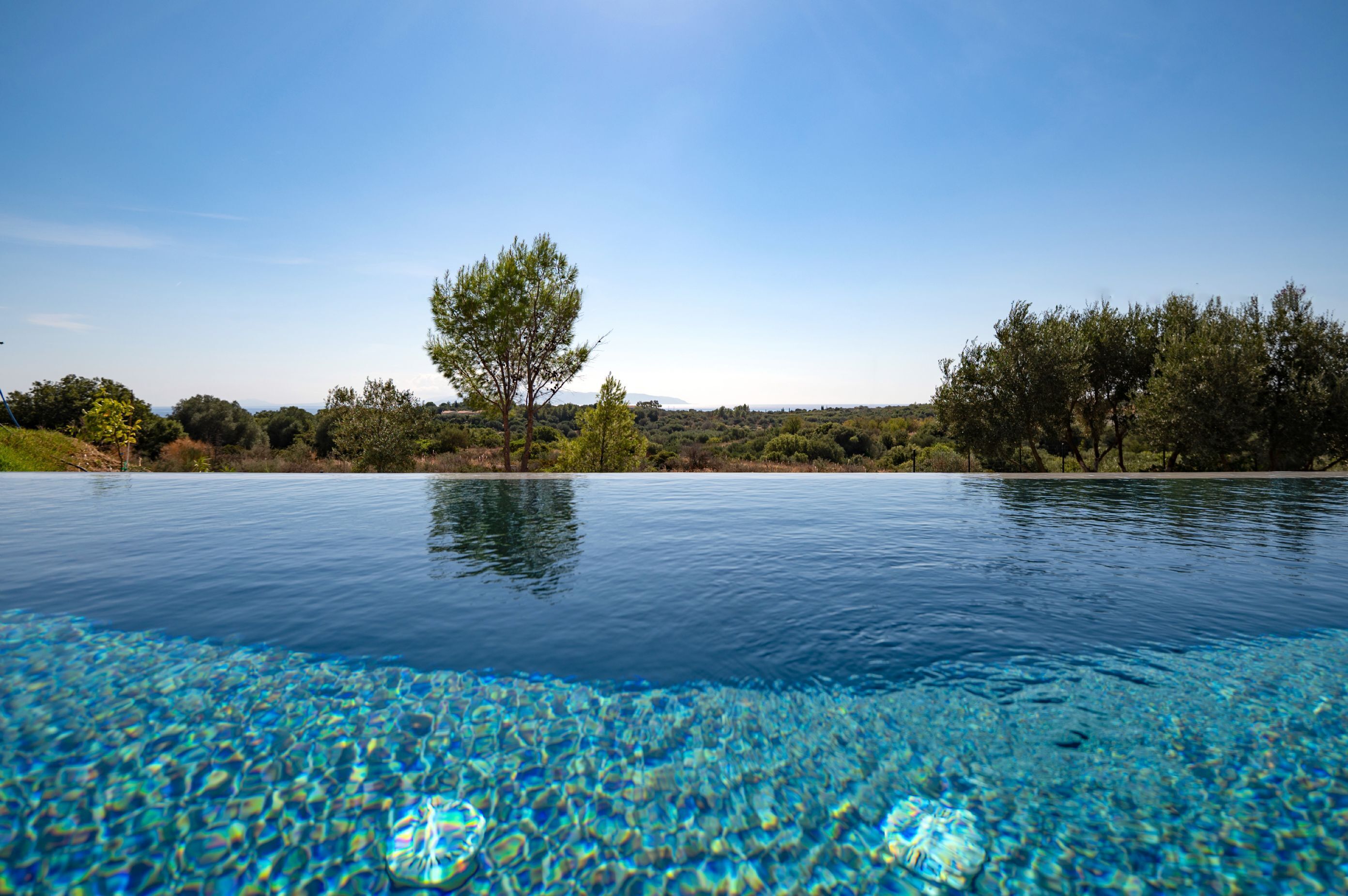 A clear pool with a view of trees and a distant landscape.