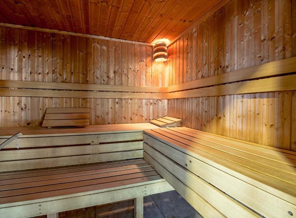 A sauna with wooden benches and a central light fixture.