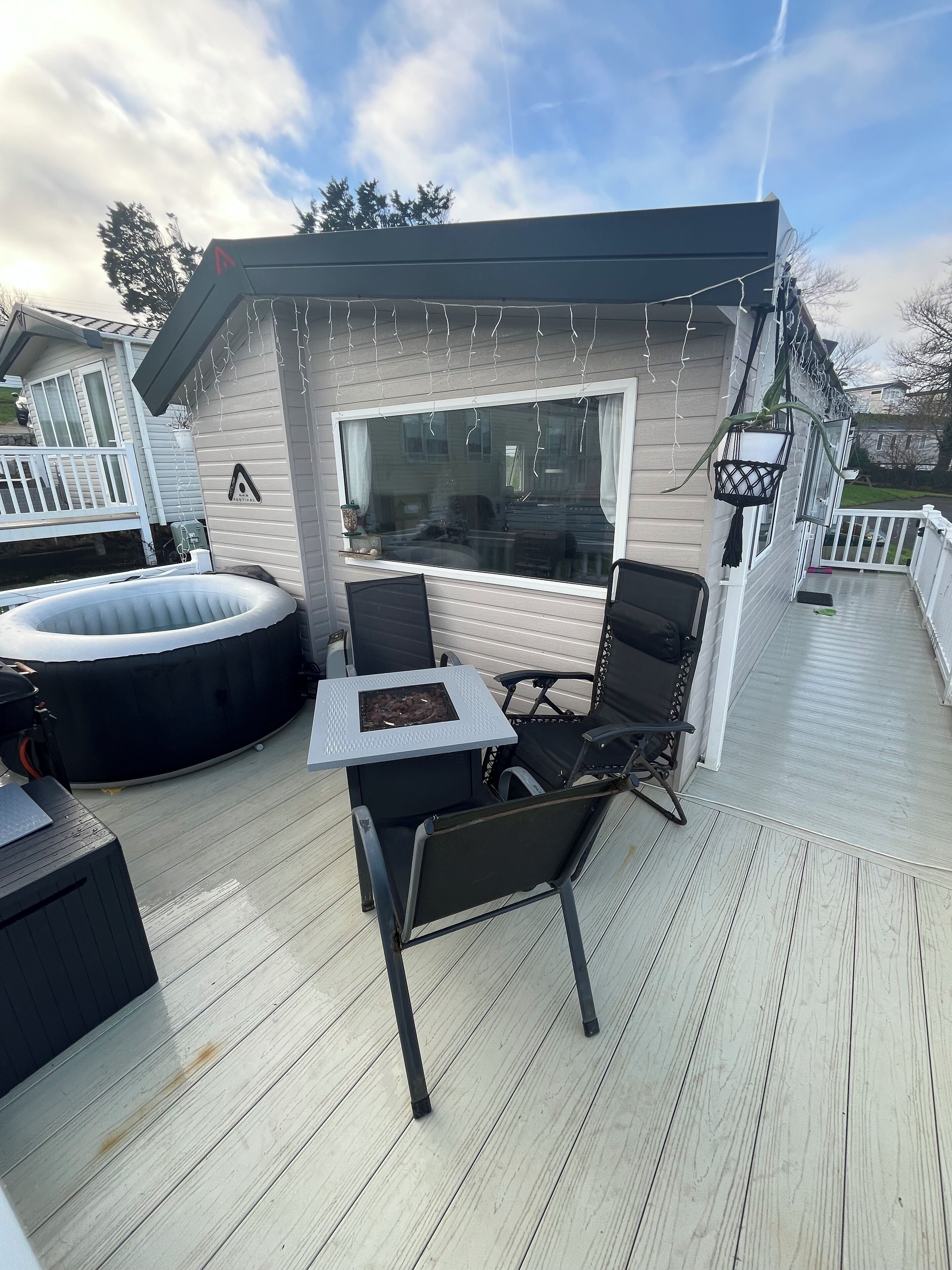 A covered outdoor deck with a hot tub, a table, and chairs.