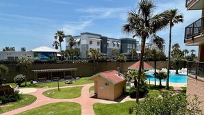 Une cour avec une piscine, des palmiers et un petit bâtiment doté d’un toit rouge.