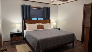A neatly arranged bedroom with a bed, two bedside tables, a ceiling fan, and a window with curtains. - Negreet Retreat#2 Clean Waterfront Midlake Toledo Bend Sleeps 12 with Hot Tub (Many)