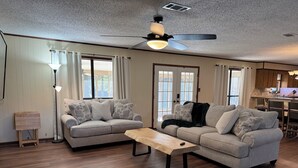 A living room with two sofas, a coffee table, a floor lamp, and a ceiling fan. - Negreet Retreat#2 Clean Waterfront Midlake Toledo Bend Sleeps 12 with Hot Tub (Many)
