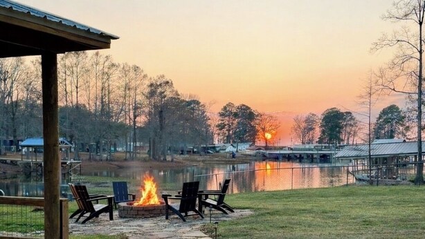 A stone pathway leading to a fire pit area with chairs, overlooking a lake and a grassy area with a wooden structure. - Negreet Retreat#2 Clean Waterfront Midlake Toledo Bend Sleeps 12 with Hot Tub (Many)