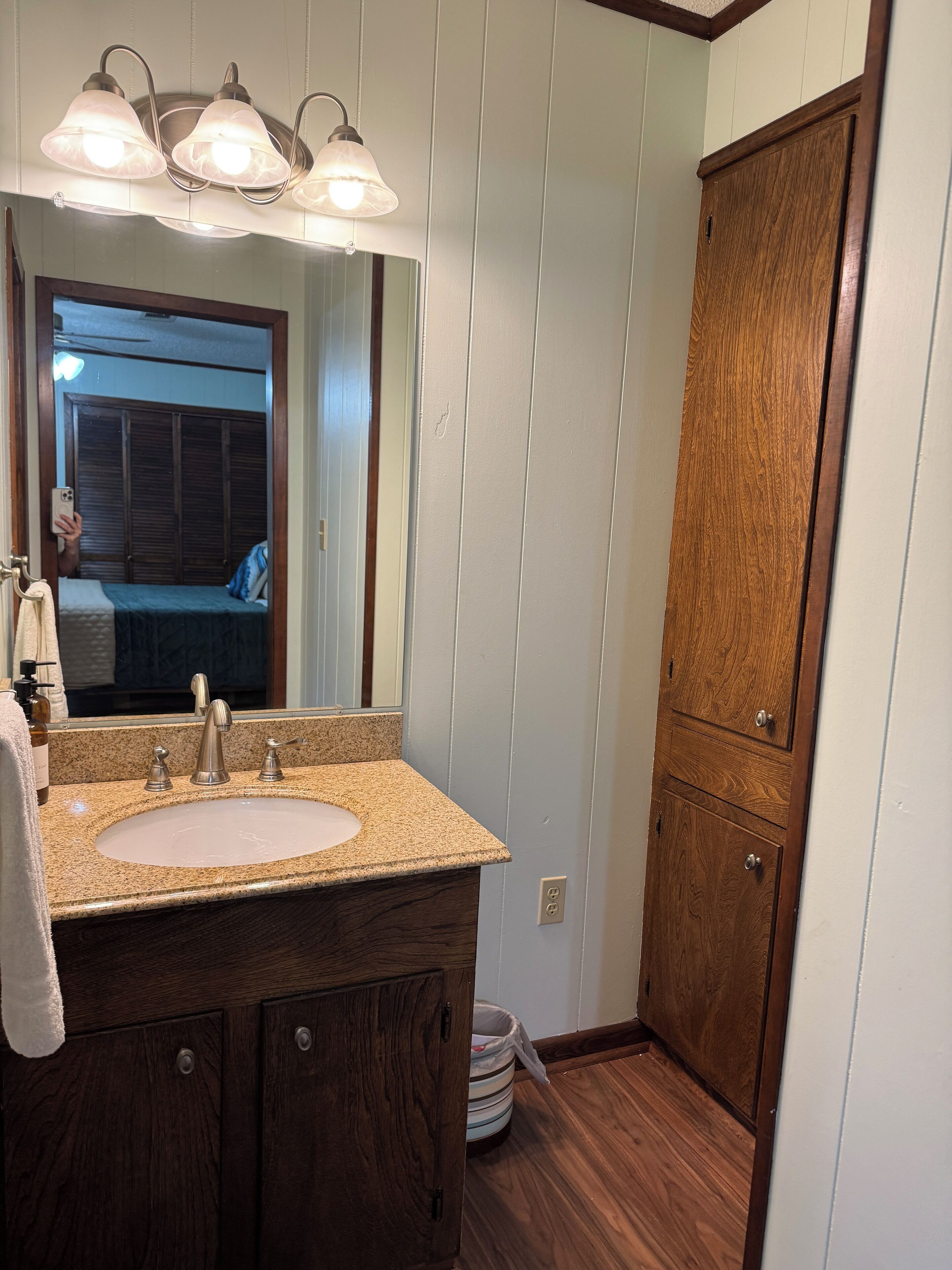 Une salle de bain avec un meuble-lavabo à deux vasques, un meuble en bois et un miroir avec éclairage intégré.