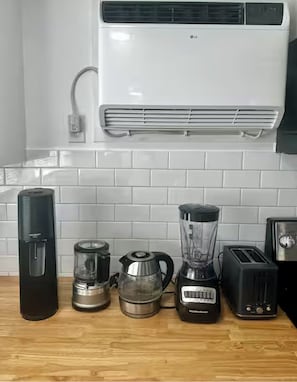 Una cocina equipada con cafetera, hervidor, licuadora, tostadora y aire acondicionado.