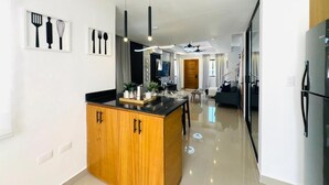 A modern kitchen with a central island, pendant lighting, and a dining area with a sofa and table. - Tranquil villa with AC and pool in Punta Cana (Punta Cana)