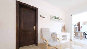 A room with a dark wooden door, a white chair, a white desk, and a cactus decoration.