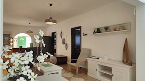 A living room with a sofa, a coffee table, a side table, a wooden cabinet, and a hanging light fixture.