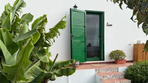 Una casa con puerta verde, una planta pequeña en maceta y una escalera que lleva a la entrada.