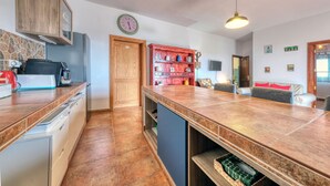 Una cocina moderna con un mueble de madera, un horno empotrado y una estantería roja.