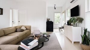 Een moderne woonkamer met een bank, salontafel en een aan de muur bevestigde televisie.