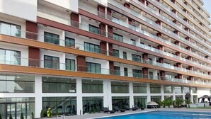 Un hôtel à plusieurs étages doté d’une piscine et de chaises longues.