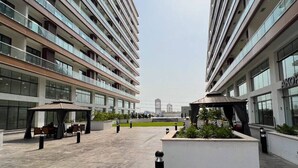 Un bâtiment moderne à étages, doté d’espaces extérieurs aménagés pour s’asseoir et d’une cour paysagée.