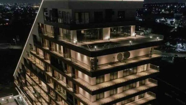 Un immeuble à plusieurs étages doté de balcons, de grandes fenêtres et d’une terrasse sur le toit.