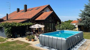 Ein Haus mit Swimmingpool, überdachter Terrasse und Garten.