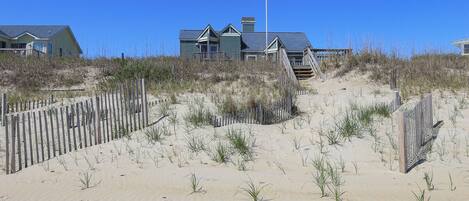 A beachfront property with a wooden staircase leading to a house.