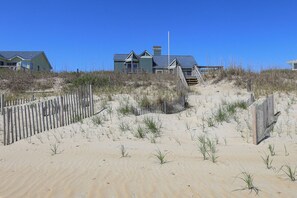 A beachfront property with a wooden staircase leading to a house.