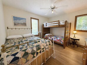 A bedroom with two beds, a ceiling fan, a painting, and a window with blinds. - Anchor Aweigh - 4 BR Home in Southern Shores w/Private Pool (Southern Shores)