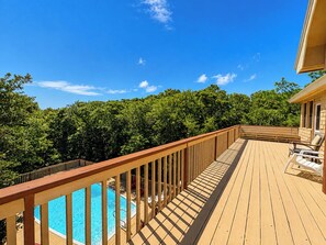 A wooden deck with a pool, surrounded by trees.