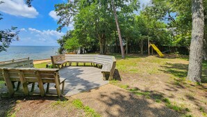 A wooden deck with benches, a playground with a slide, and a view of the sea. - Anchor Aweigh - 4 BR Home in Southern Shores w/Private Pool (Southern Shores)