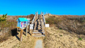 A wooden boardwalk leading to a beach house with a blue roof. - Anchor Aweigh - 4 BR Home in Southern Shores w/Private Pool (Southern Shores)