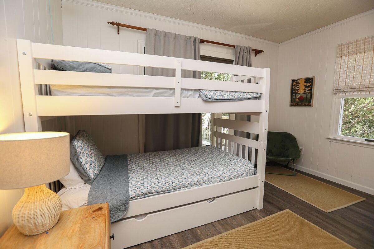 A bunk bed with a patterned mattress, a bedside lamp, and a small table.