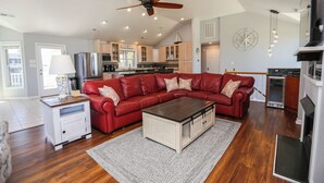 Un salón espacioso con un sofá modular rojo, una mesa de centro de madera y un ventilador de techo.
