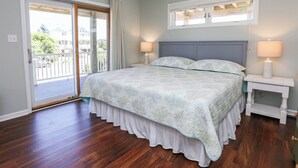 Un dormitorio con una cama grande, una puerta corrediza de vidrio a un balcón y dos lámparas de noche.