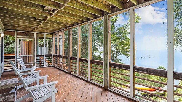 A covered wooden deck with Adirondack chairs and a view of the water. - Wilson's Landing - Enjoy beautiful Sound Views from this Soundfront 4BR home in Duck (Duck)