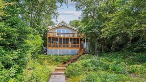A house with a wooden deck and a staircase leading to a second floor. - Wilson's Landing - Enjoy beautiful Sound Views from this Soundfront 4BR home in Duck (Duck)