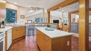 A spacious kitchen with wooden cabinets, a large island, and a view of the outdoors through large windows. - Wilson's Landing - Enjoy beautiful Sound Views from this Soundfront 4BR home in Duck (Duck)