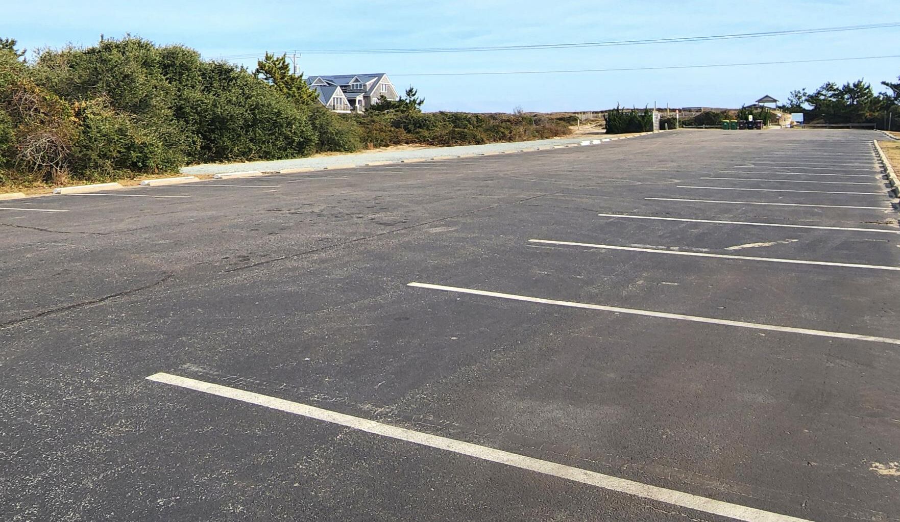 Un grand parking vide, avec des emplacements clairement délimités et un bâtiment en arrière-plan.