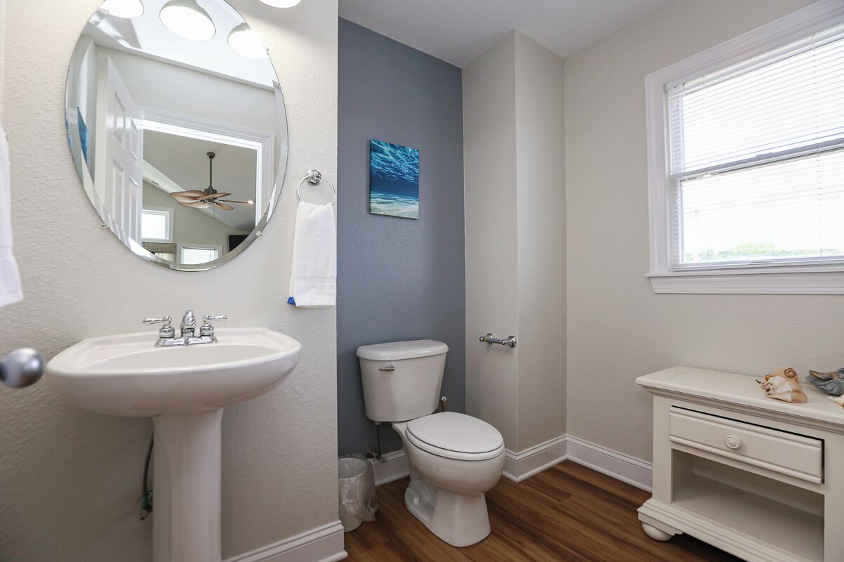 Une salle de bain avec un lavabo sur colonne, des toilettes et un meuble-lavabo avec un miroir.