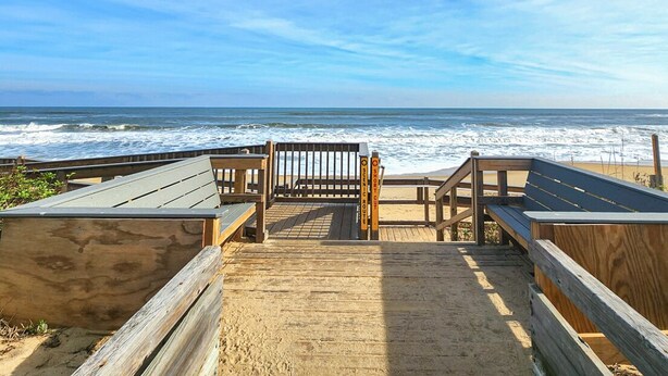 A wooden boardwalk leading to a beach with a wooden bench and a sign indicating a short distance to the beach. - Serendipity on the Sound - Beautiful 4 BR Soundfront Home With Amenities Galore (Southern Shores)