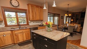 A kitchen with wooden cabinets, a granite countertop, and a central island. - Serendipity on the Sound - Beautiful 4 BR Soundfront Home With Amenities Galore (Southern Shores)