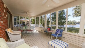 A covered outdoor area with wicker furniture, a table, and chairs, overlooking a body of water. - Serendipity on the Sound - Beautiful 4 BR Soundfront Home With Amenities Galore (Southern Shores)