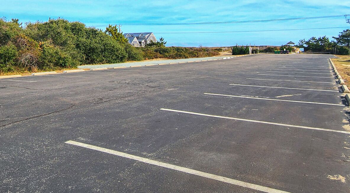 A large, empty parking lot with clearly marked parking spaces and a building in the background.