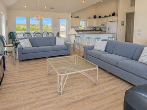 A spacious living room with a sofa, a coffee table, and a dining area with chairs.