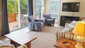 A living room with a sofa, two armchairs, a TV, and a fireplace.