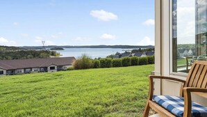 Un balcón con vista a un lago, una silla y un edificio al fondo.