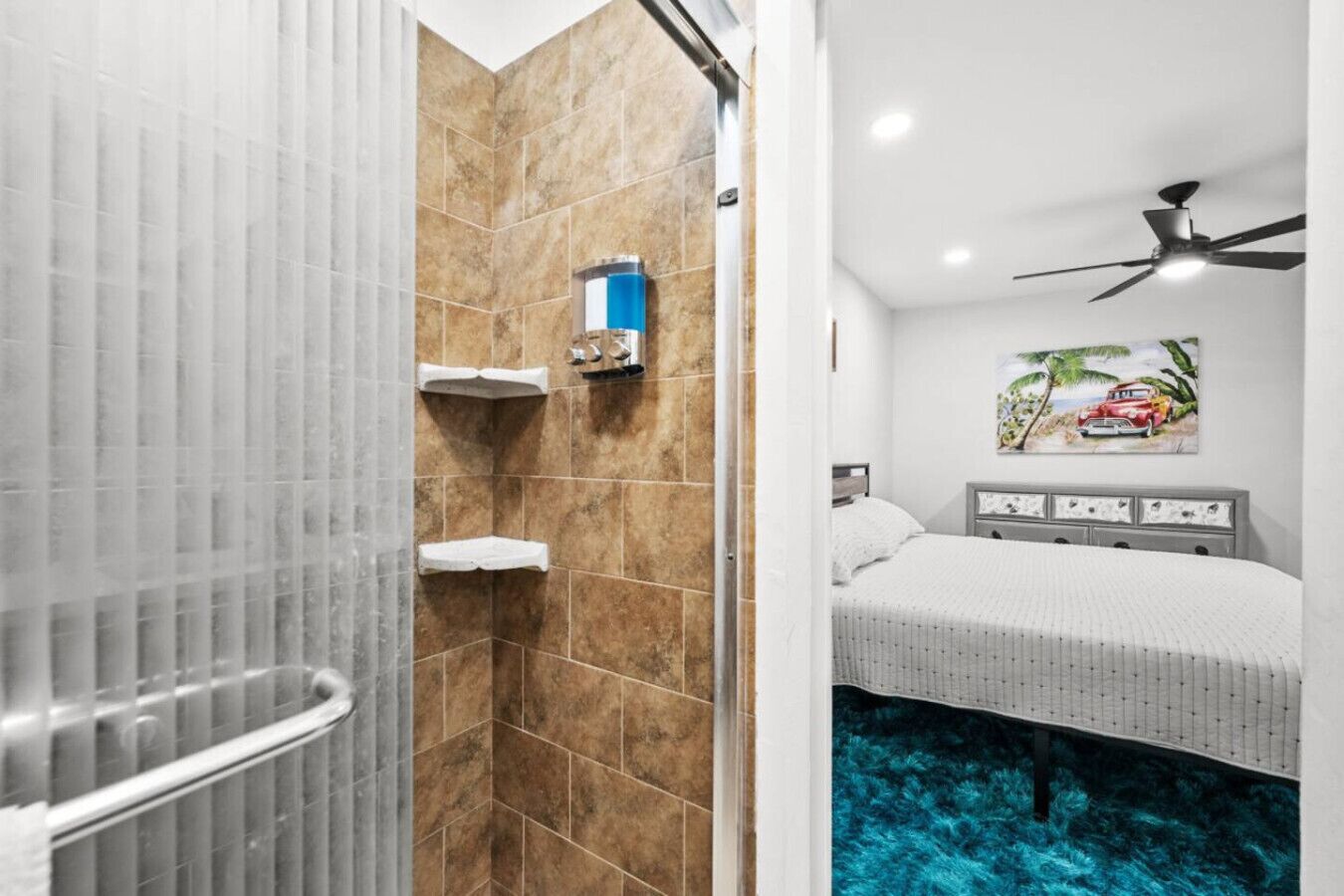 Un baño con ducha, inodoro y una cama sobre una alfombra azul.