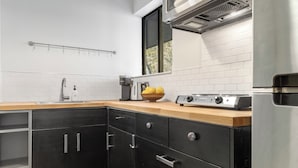 A modern kitchen with a stainless steel refrigerator, a wooden countertop, and black cabinets.