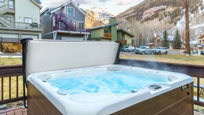 A hot tub on a deck with a mountain backdrop.