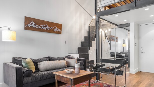 A modern living room with a sofa, coffee table, and a staircase leading to an upper level.