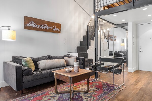 A modern living room with a sofa, coffee table, and a staircase leading to an upper level.