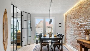 A dining area with a brick wall, a wooden table, and chairs. - Cozy home in Thyborøn with WiFi (Thyborøn)