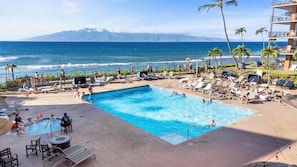 Relax by the oceanfront pool, surrounded by lounge chairs and umbrellas, with breathtaking views of the surrounding mountains.