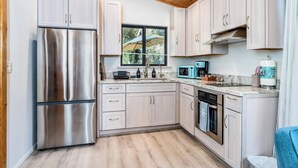 A modern kitchen with stainless steel appliances, light-colored cabinets, and a wooden ceiling. - Meadow View Nest - Charming Studio in Oakhurst [Sleeps 3] (Oakhurst)