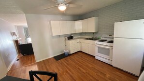 Una cocina compacta con armarios blancos, estufa y refrigerador.