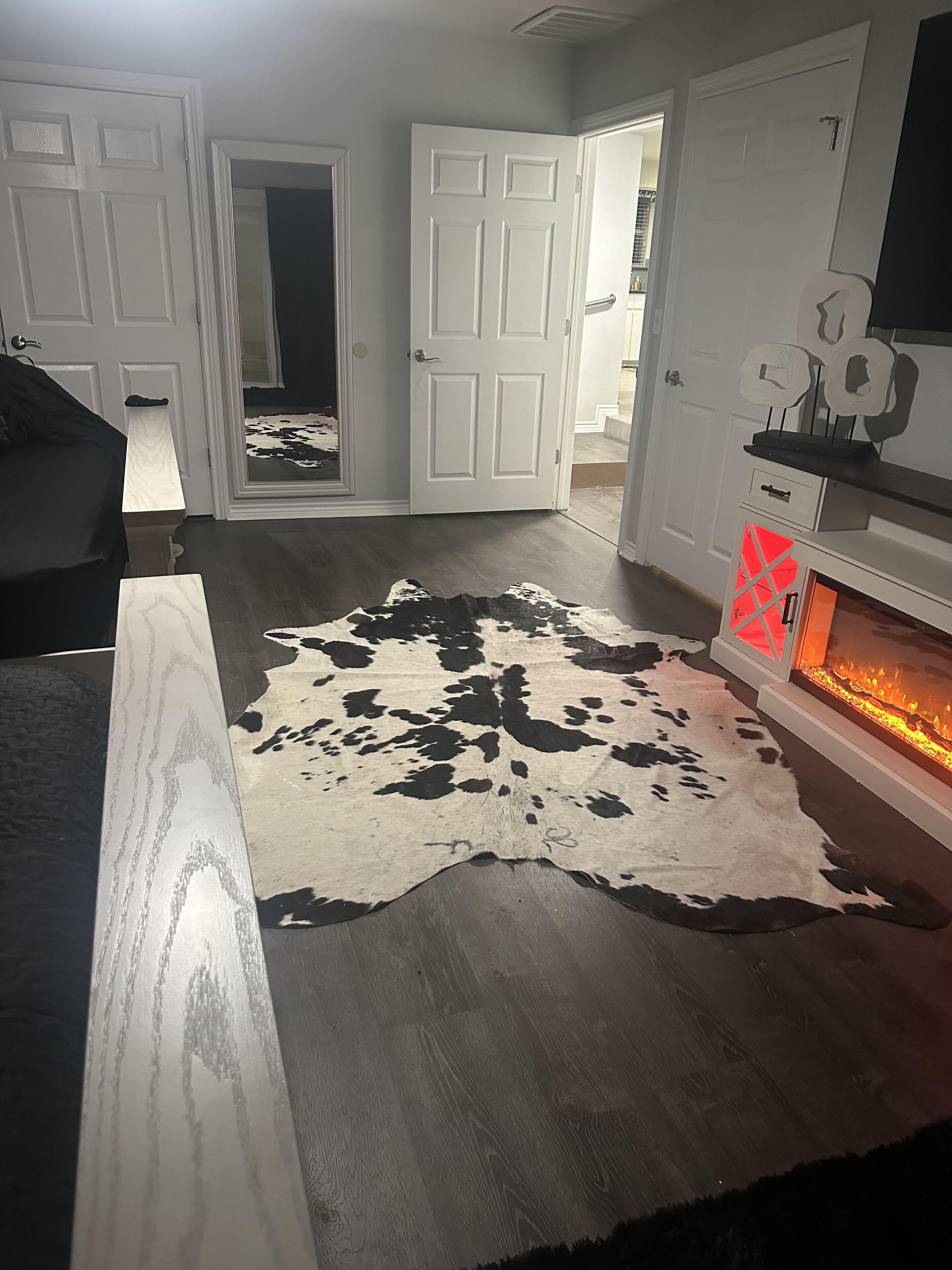 A living room with a large cowhide rug, a fireplace, and a television mounted on the wall.